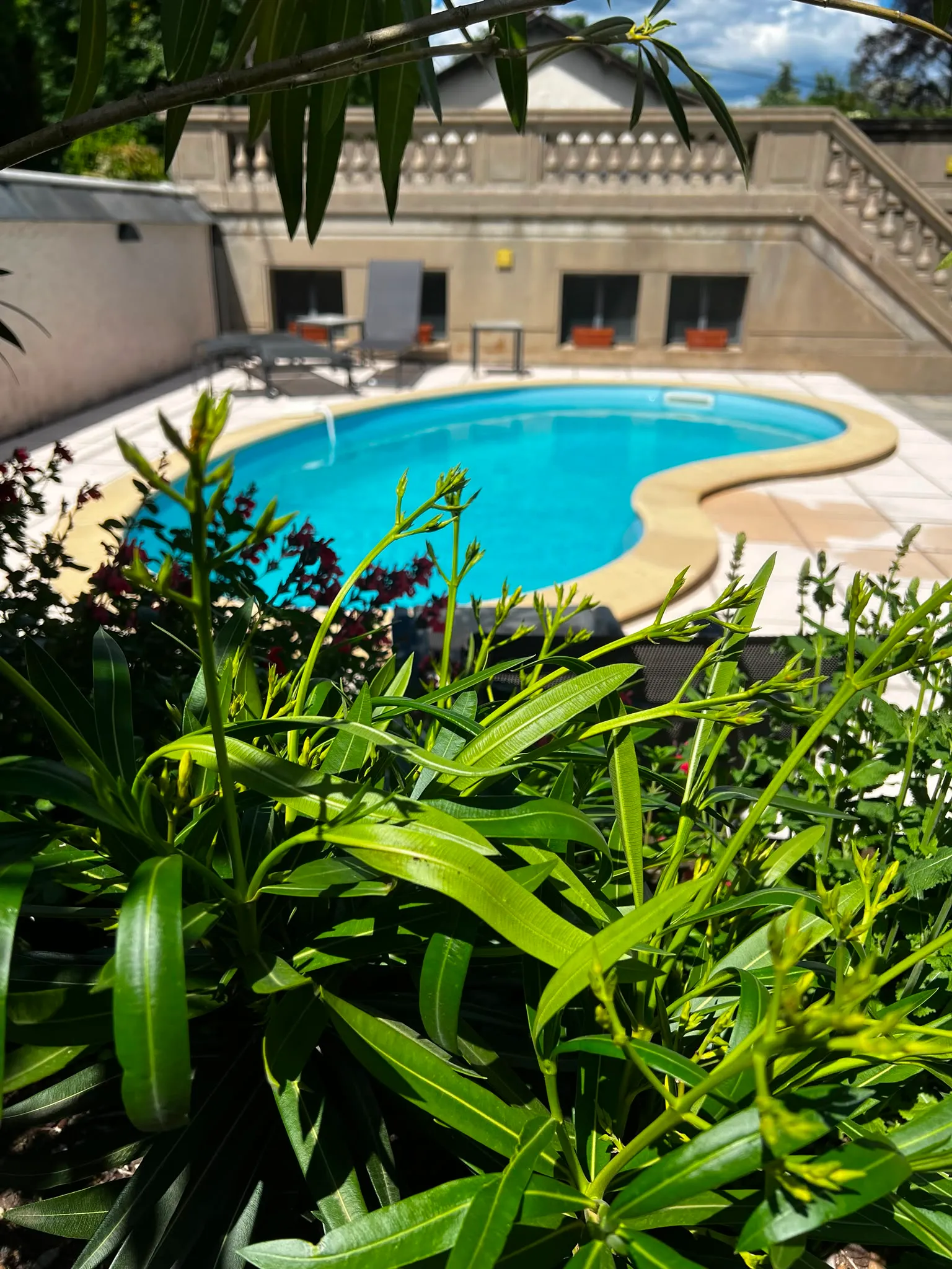 East face of la Villa de Mazamet, pool in the foreground on a clear summer day.